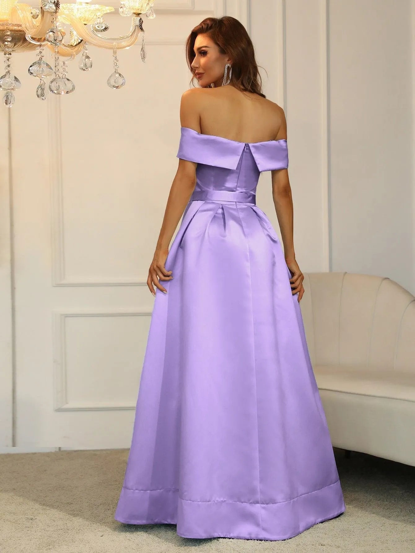 Vestido largo lila con escote off shoulder y cinturón decorativo.